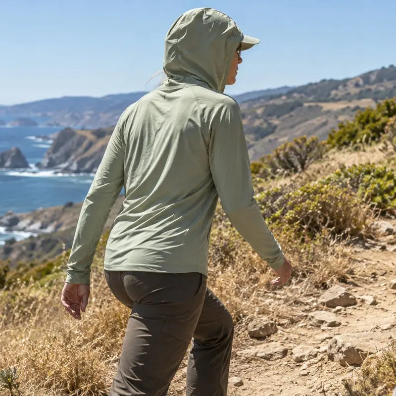 Illustrative application scene of a hiker in a lightweight sun hoodie on a coastal path