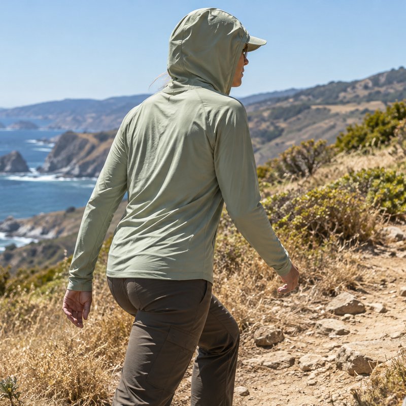 Illustrative application scene of a hiker in a lightweight sun hoodie on a coastal path